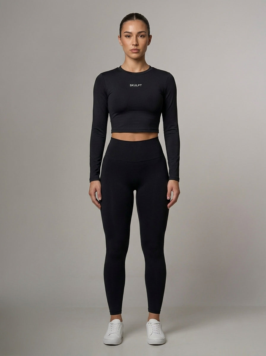 black essential long-sleeve crop top from Skulpt and leggings with a visible brand logo on a gray background